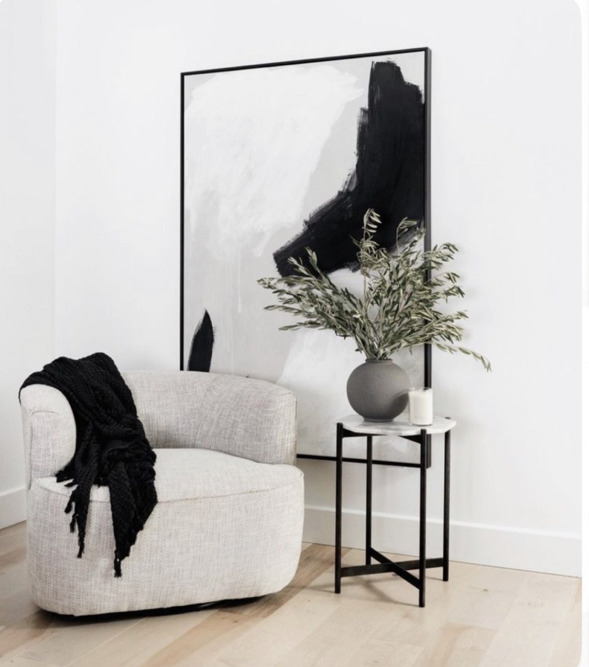 Bright natural reading corner with a cream chair, black accents, and greenery